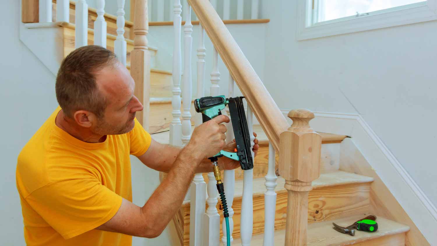 Man installing wooden railing for stairs