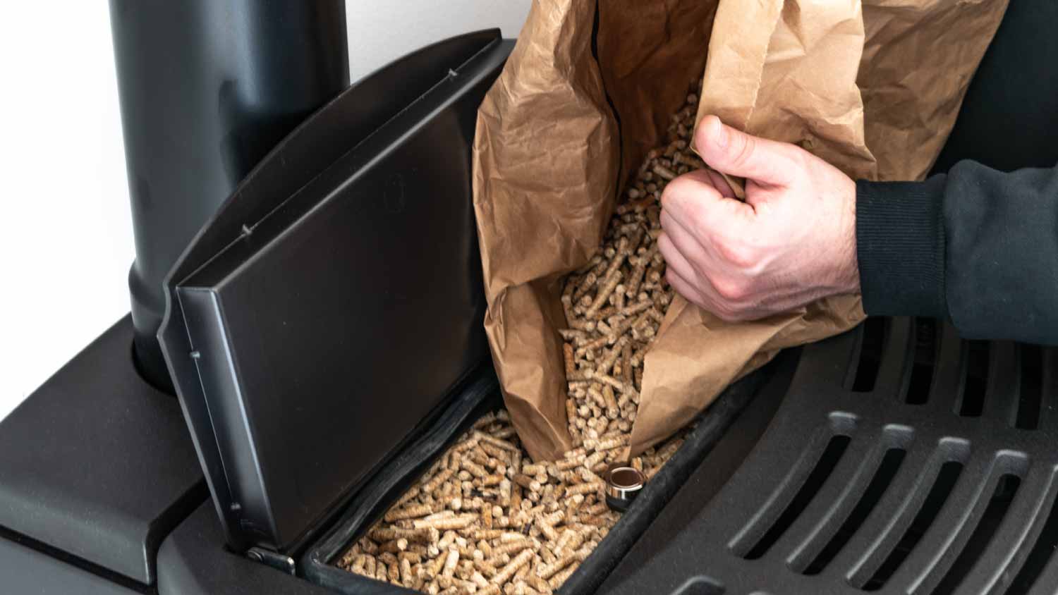 Man loading pellet stove with granule bag