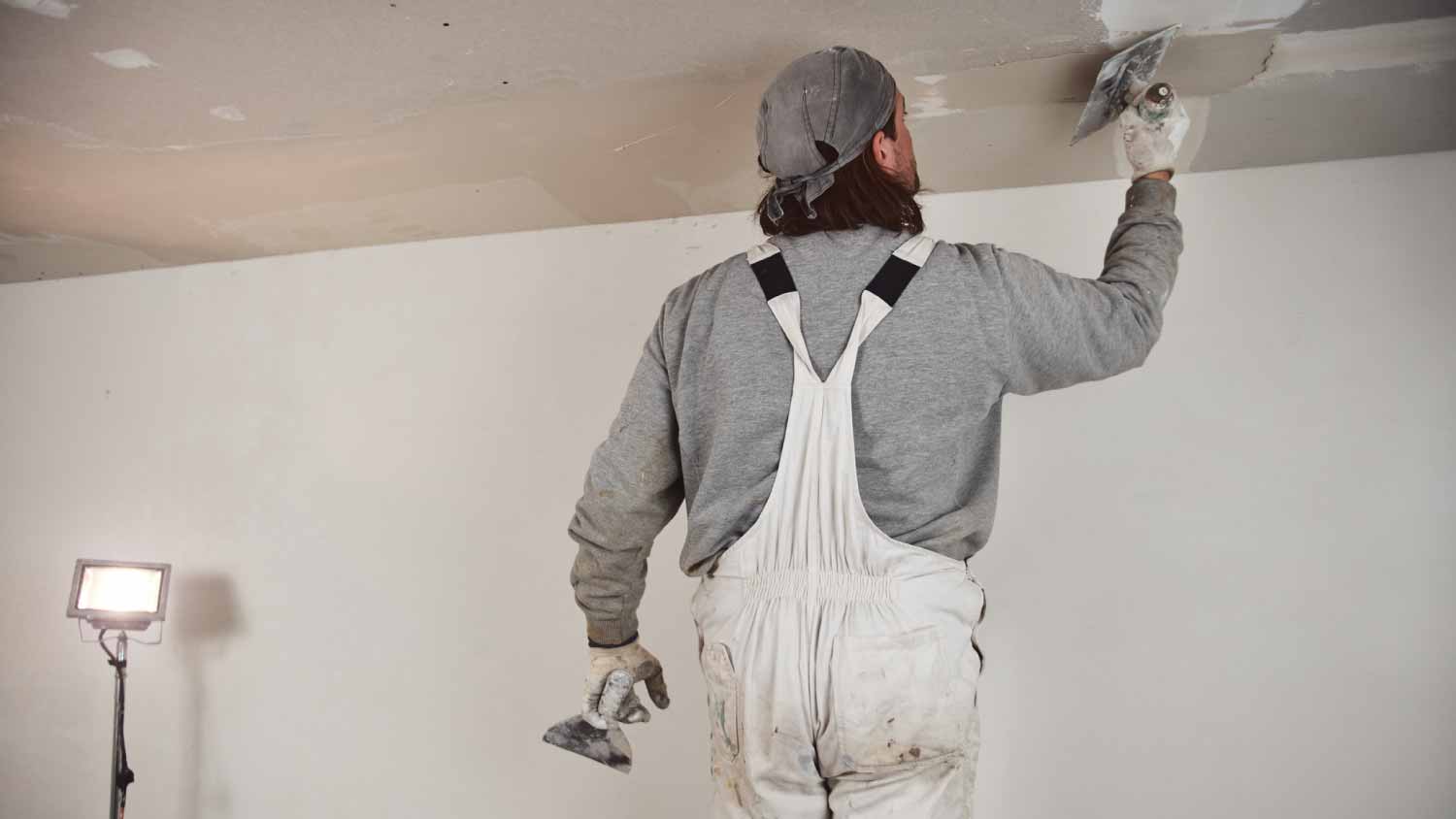 Man plastering walls inside the house