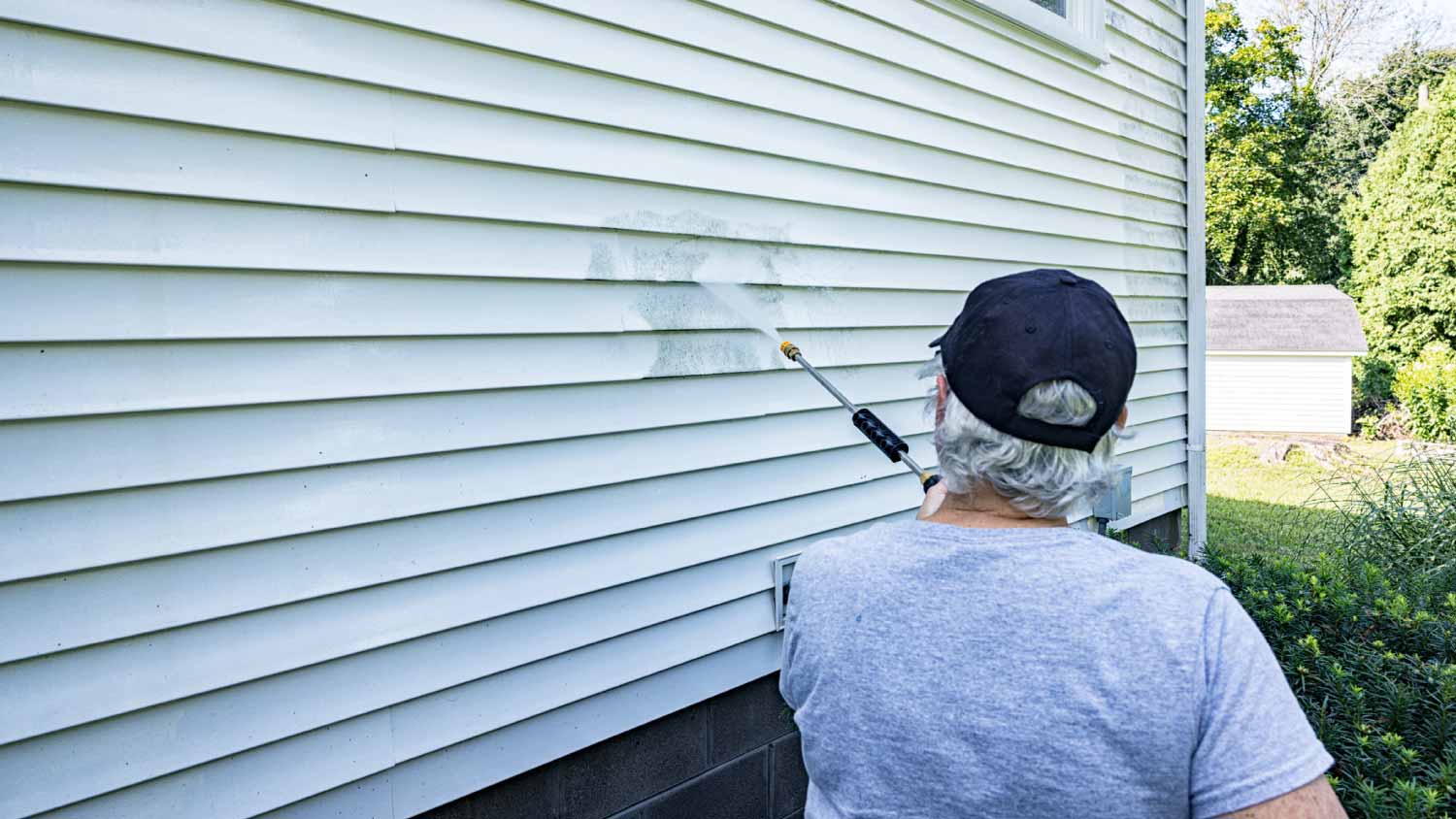 Man power washing house vinyl siding