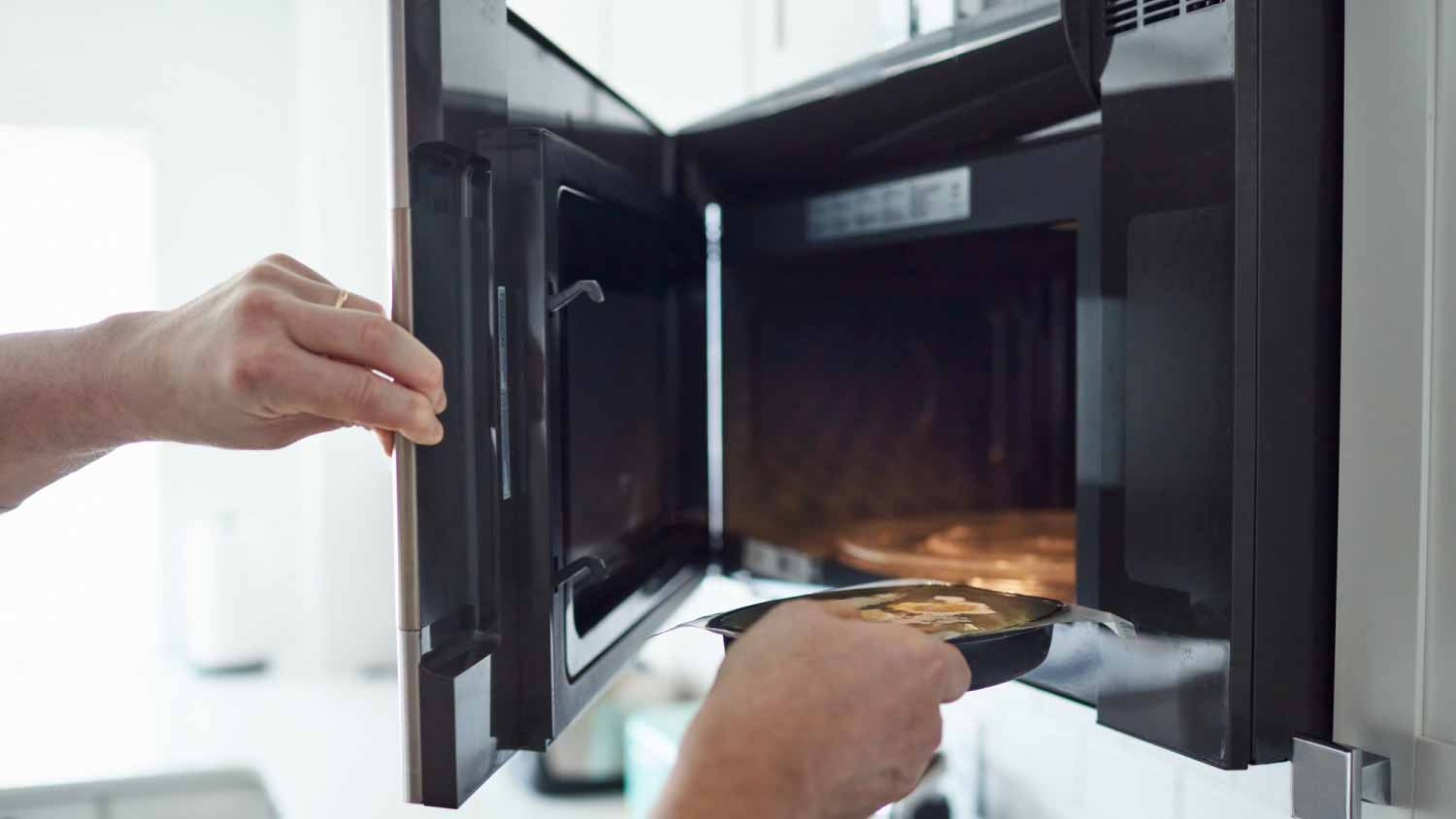 Man putting food into a microwave