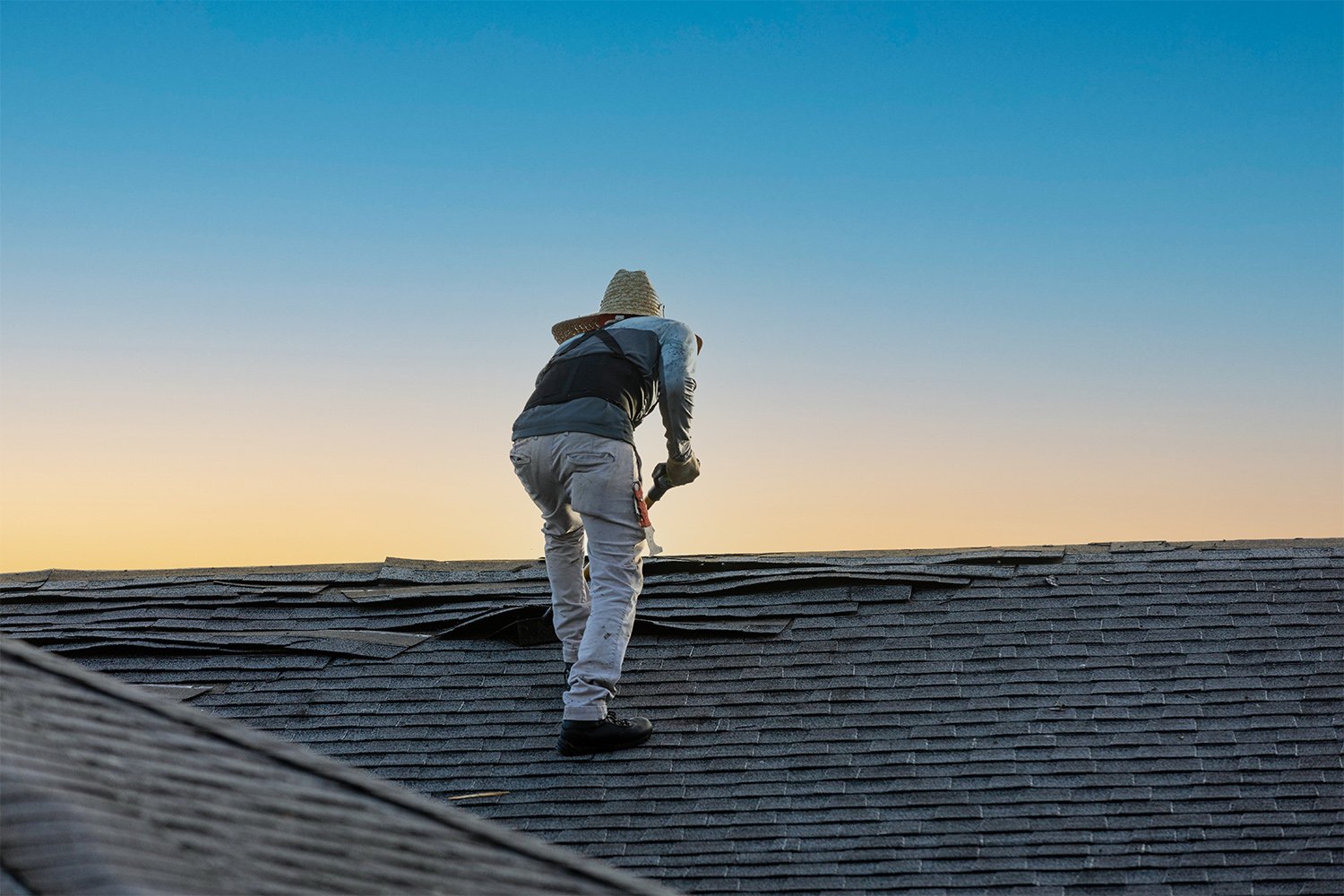 Man removing shingle roofing