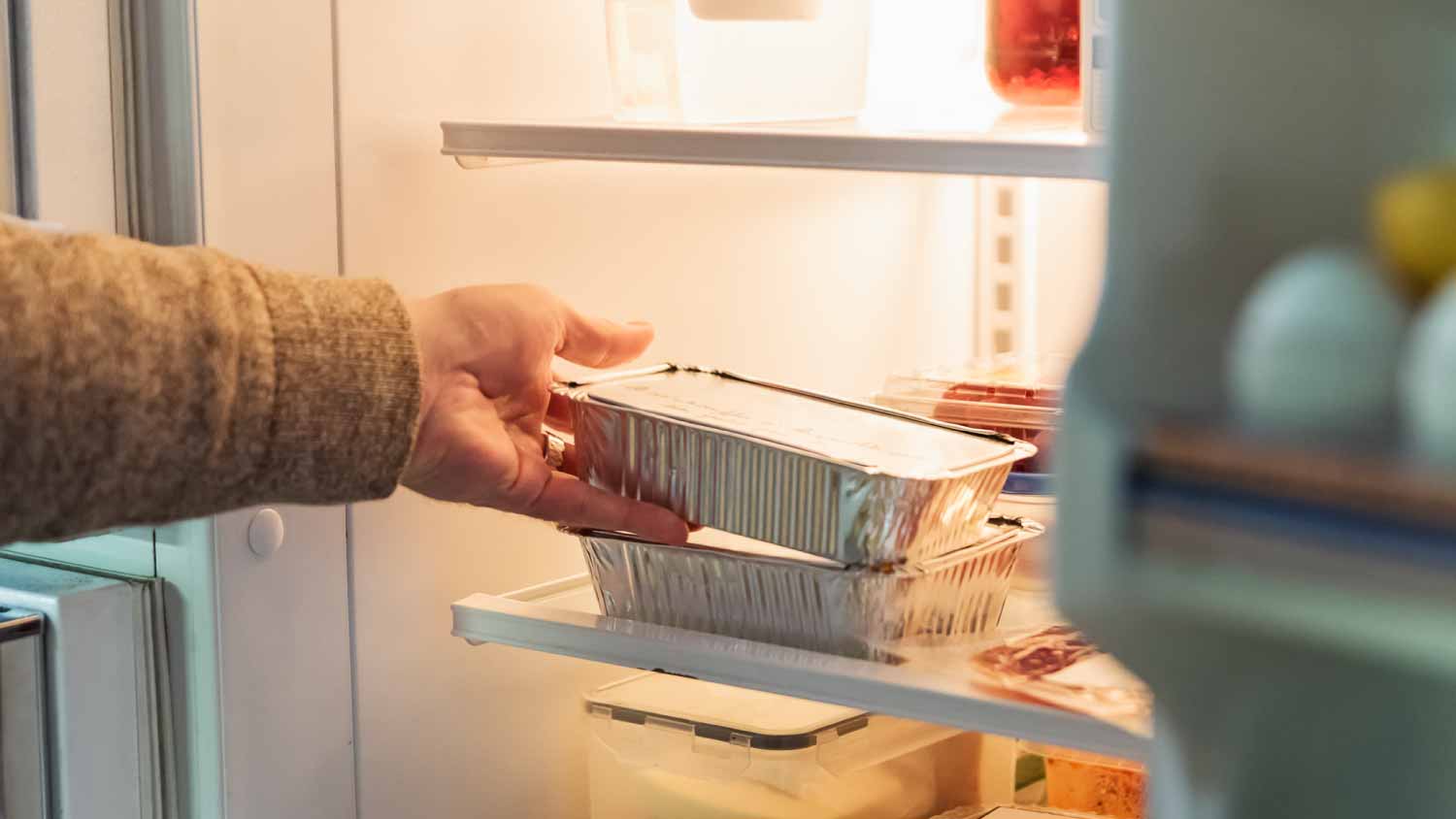 Man taking takeout meal out of refrigerator