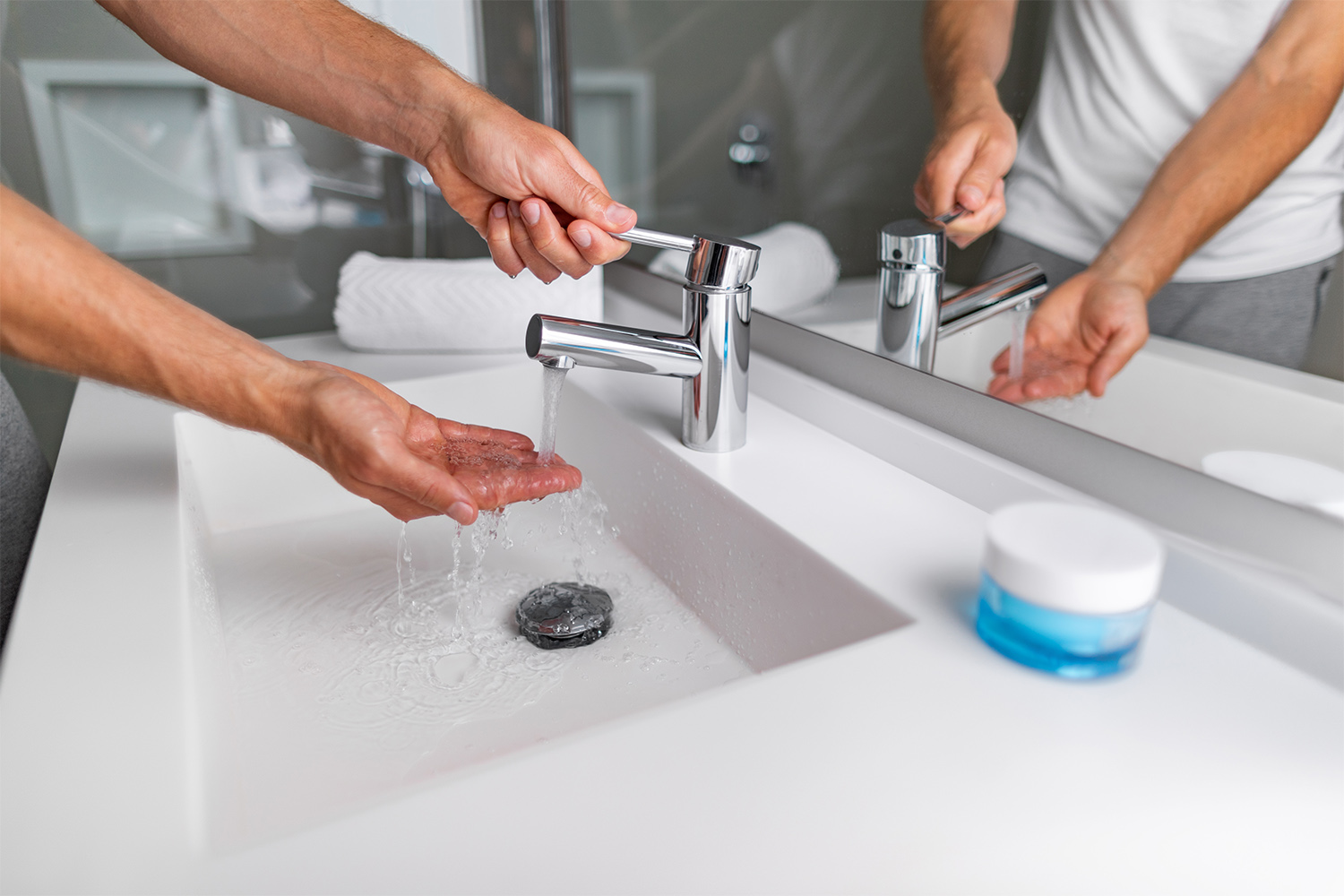 Man testing water temperature of bathroom sink