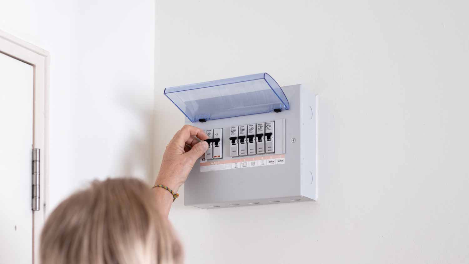 Man turning on a switch on an electrical panel