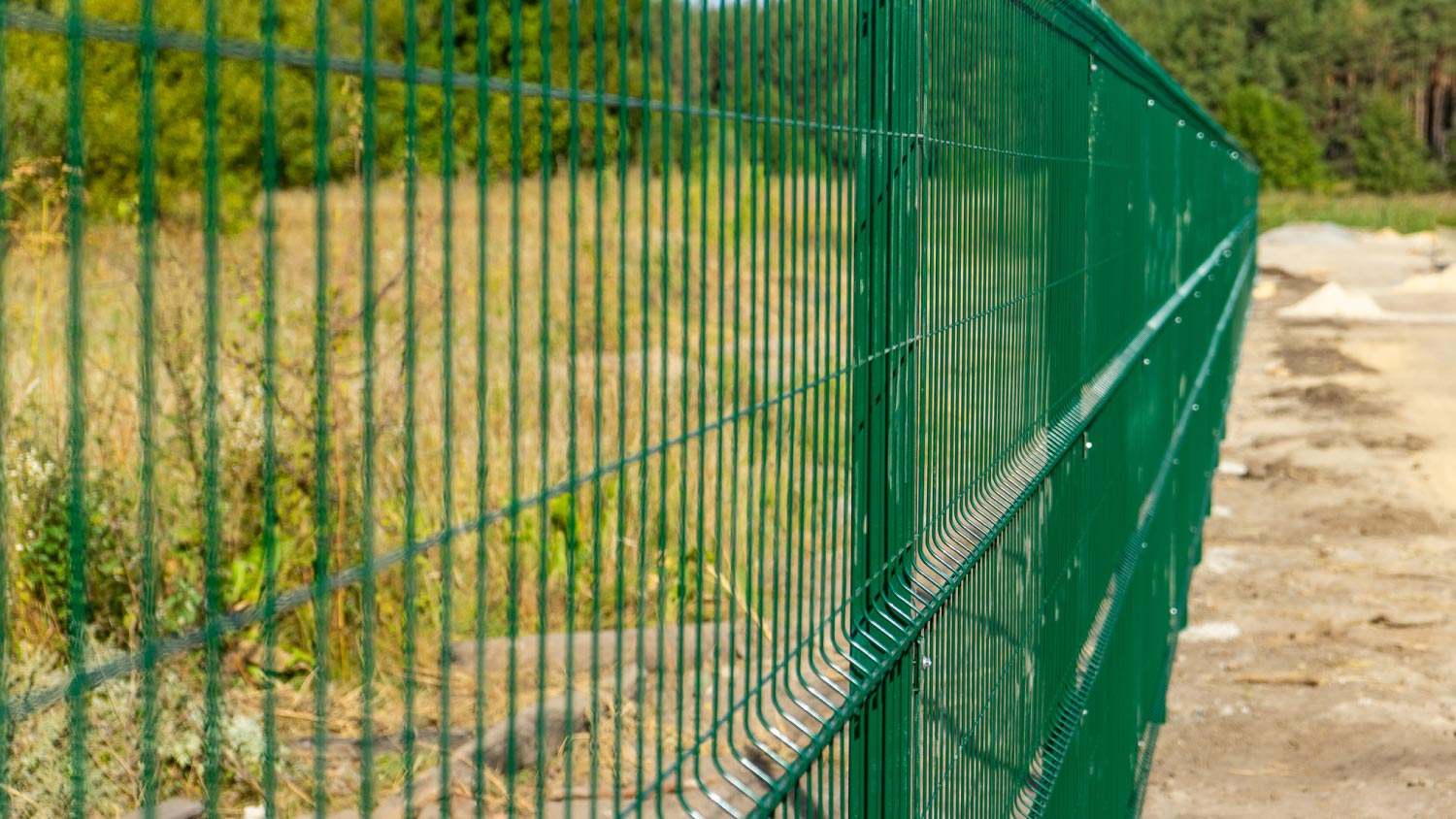 A metal fence wire with grass in the background