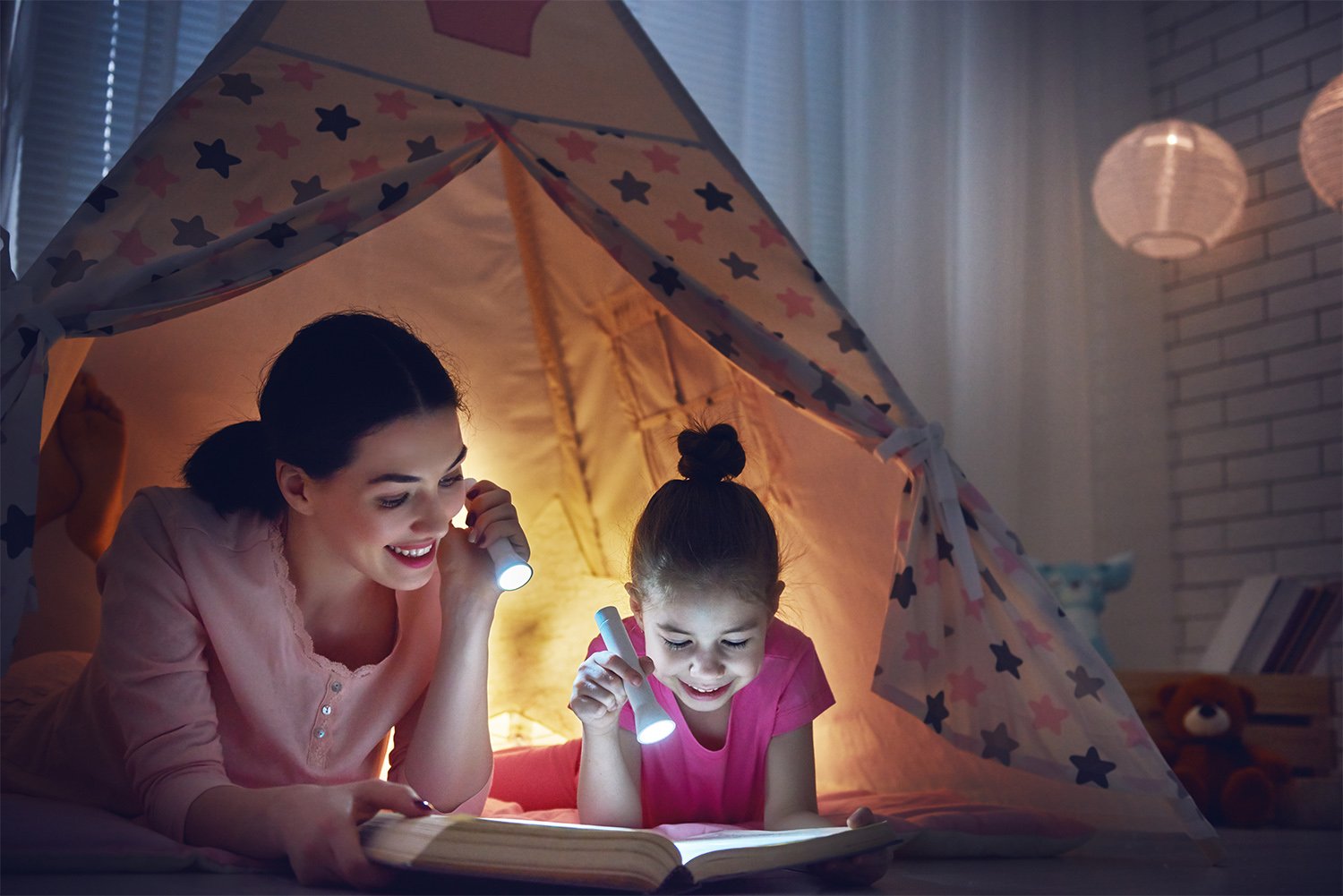 Mom and daughter reading by flashlight