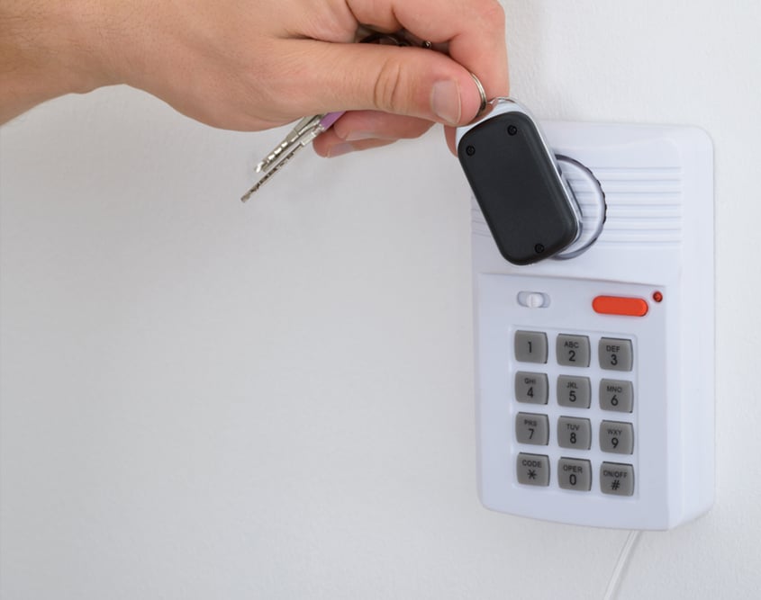 man holding key fob to communicate with house alarm