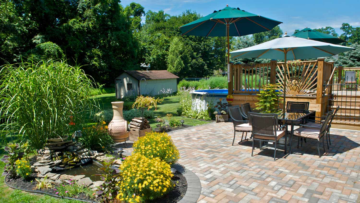 Backyard brick patio with pool, deck, and table