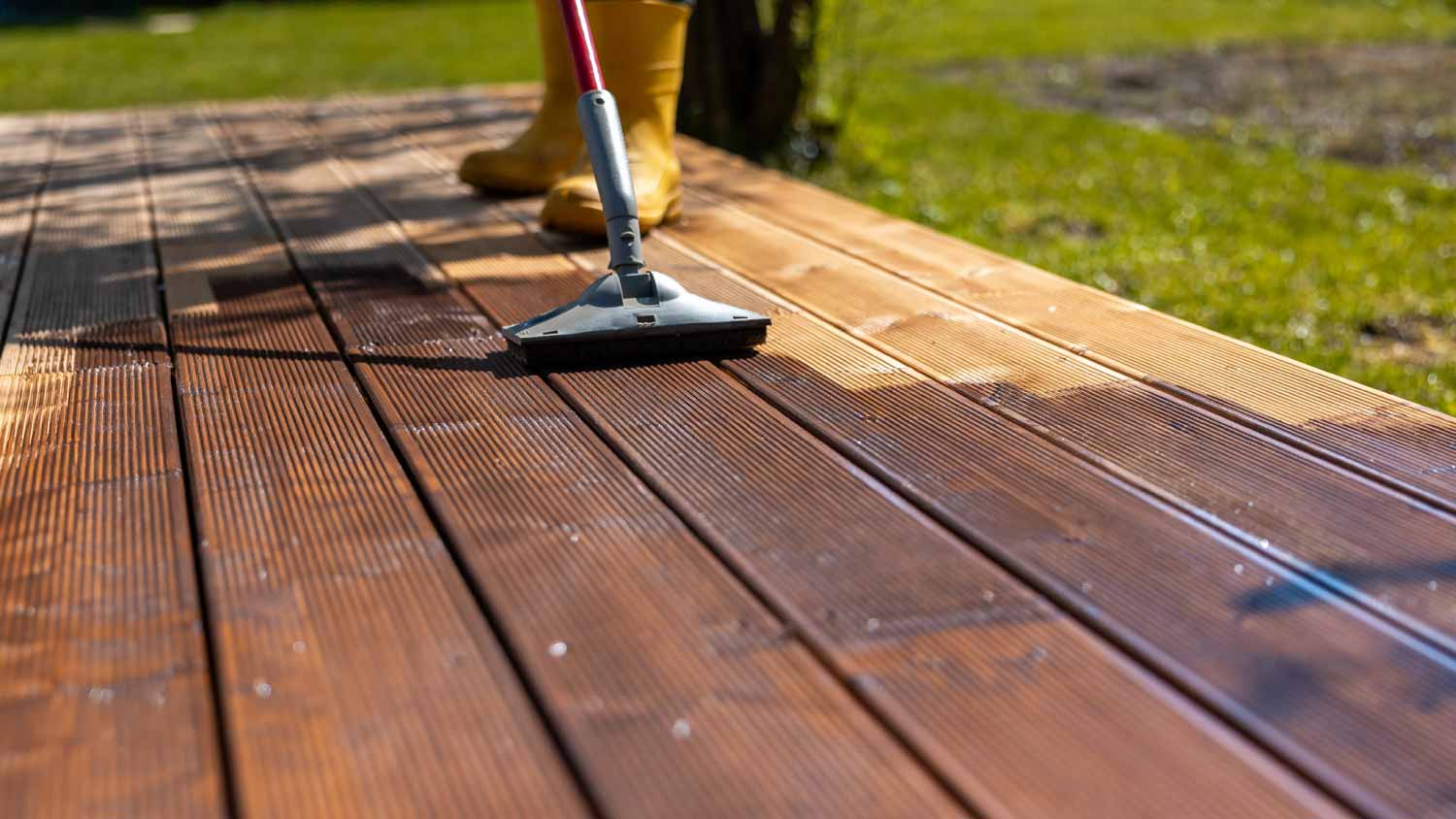 Person applying stain to a wooden deck