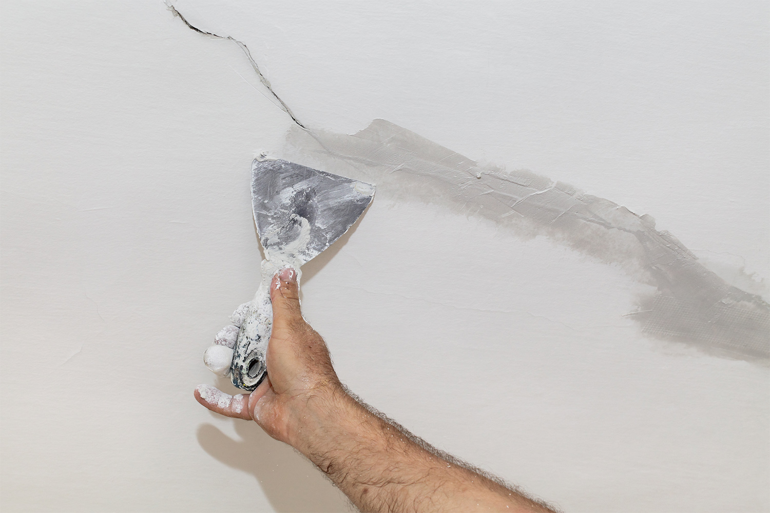 Person fixing a crack in the ceiling