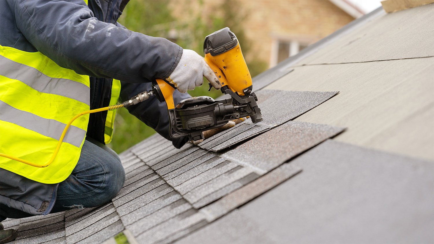 Person working on roof shingles