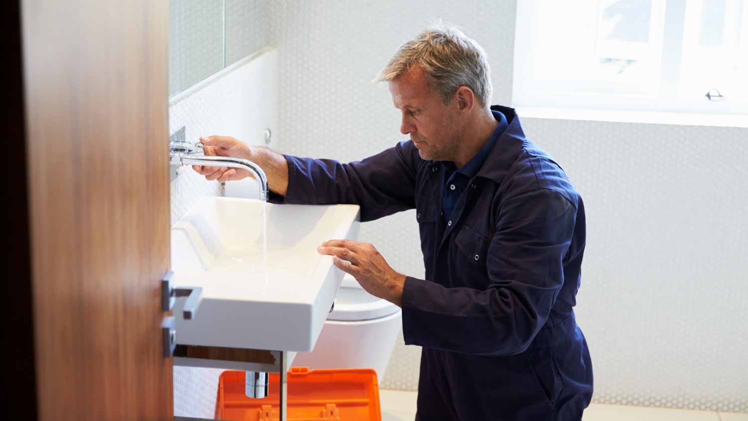 Plumber checking sink in bathroom
