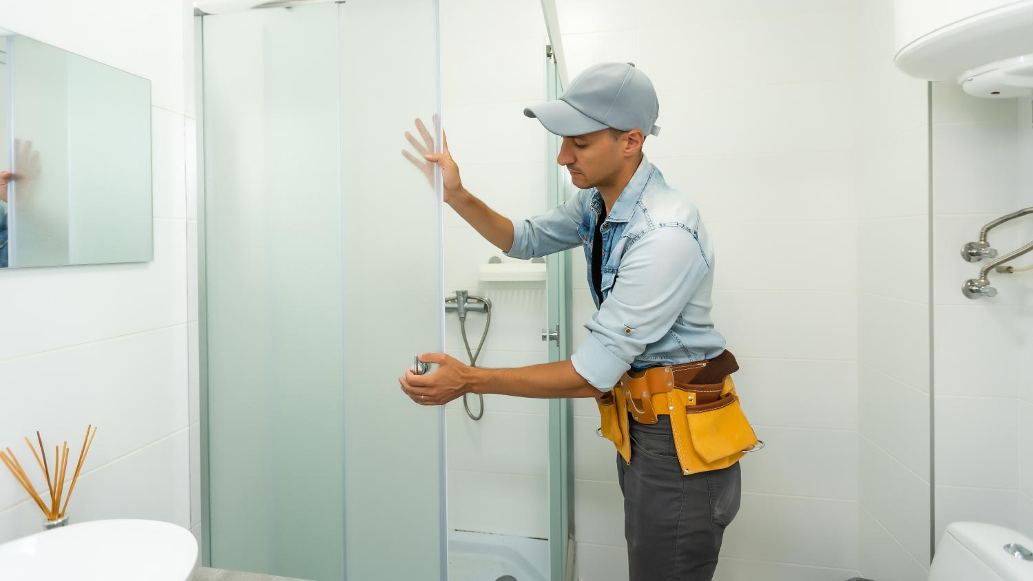 A plumber installing a shower cabin in bathroom