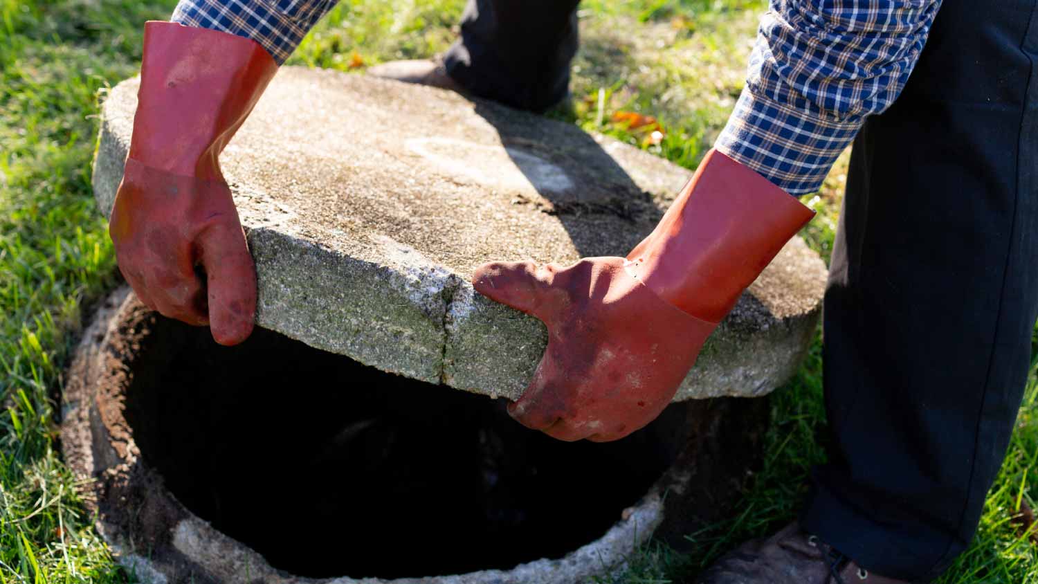 Plumber lifting up cover of septic tank