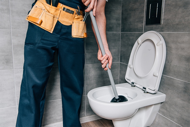Plumber using a plunger to fix toilet