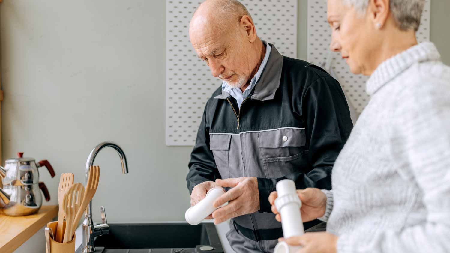 Plumber with senior woman repairing kitchen sink