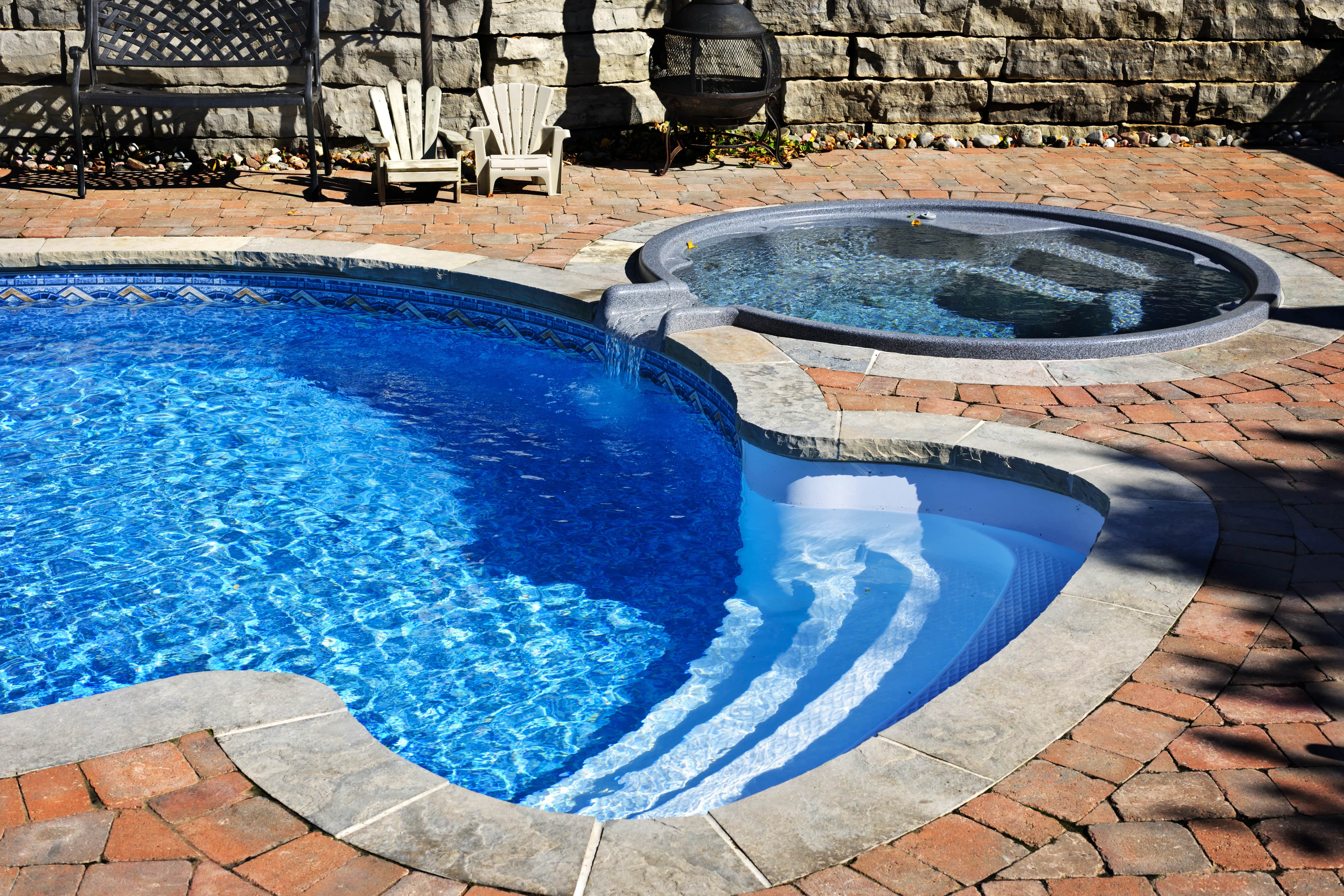 An inground swimming pool with an attached hot tub