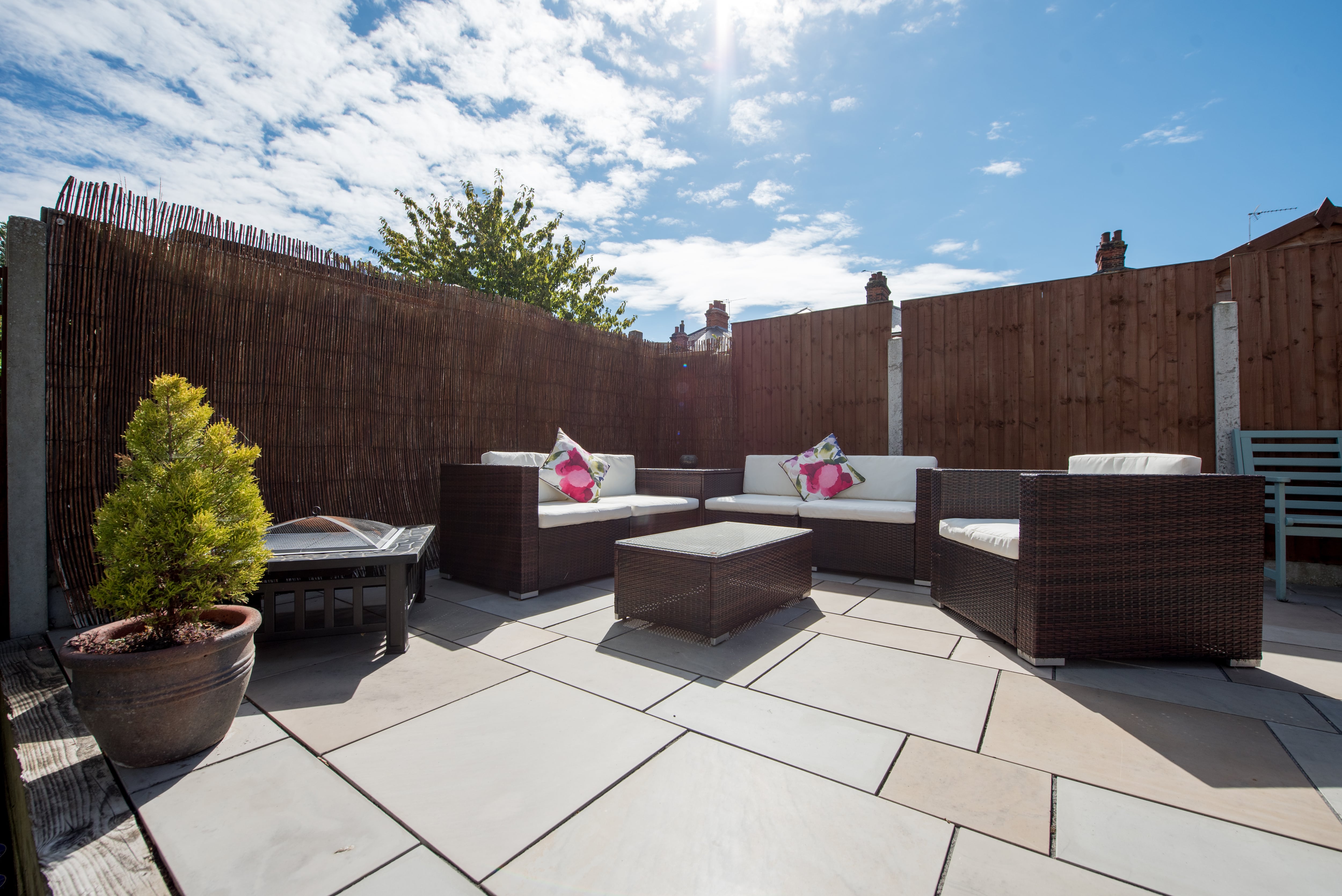 A backyard lounge area surrounded by tall bamboo and wooden fencing