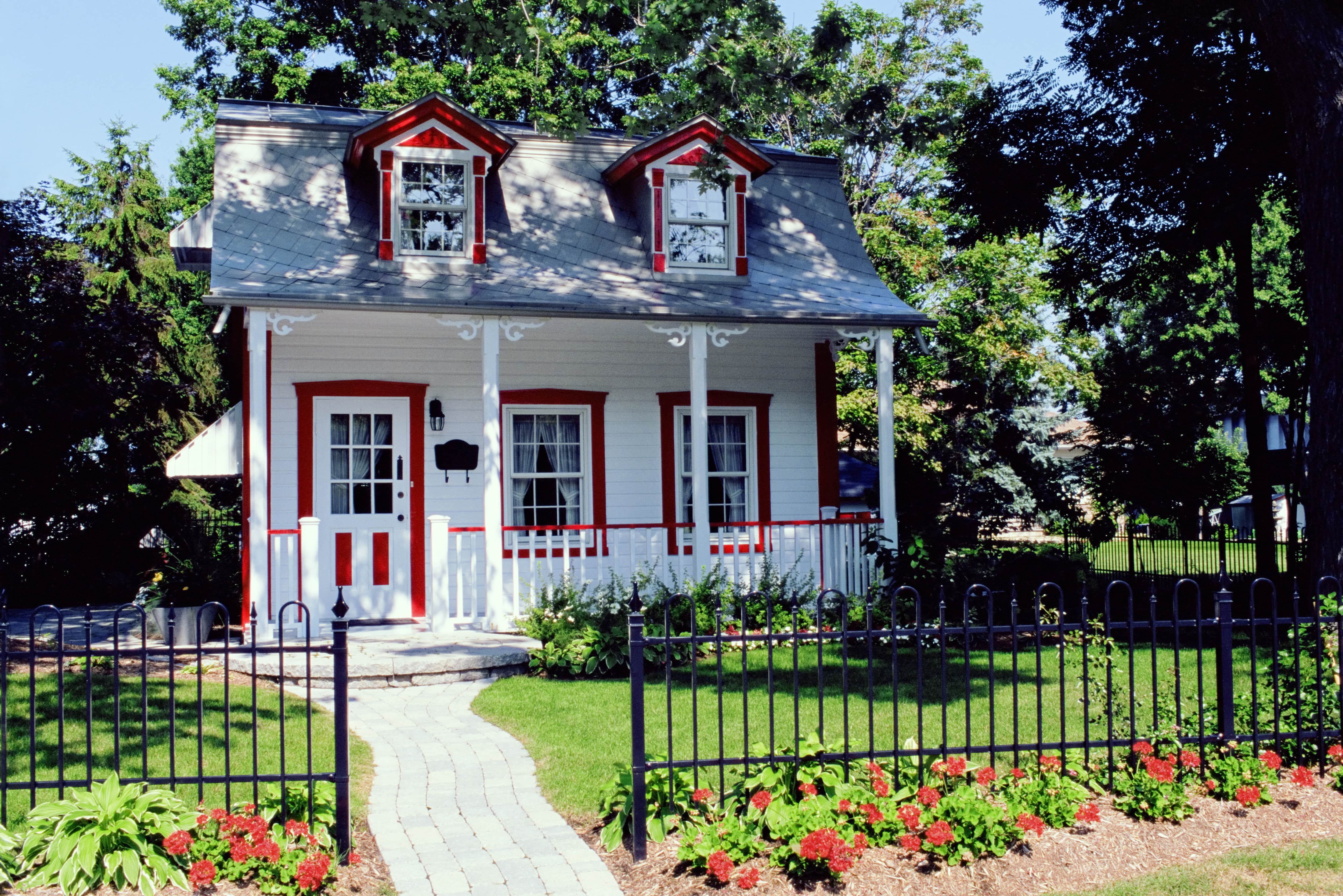 A small white house with a surrounding iron fence