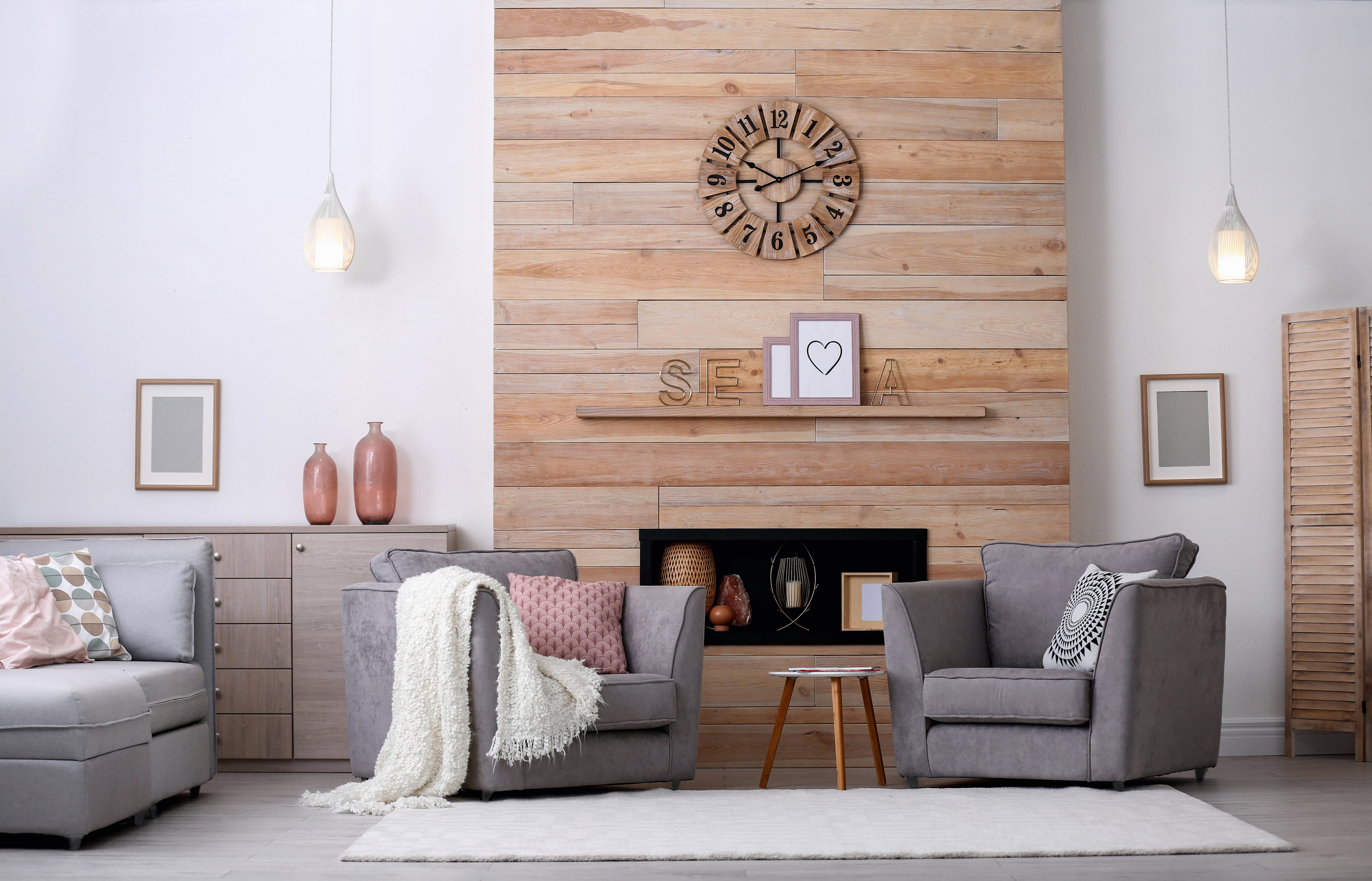 Living room with wooden shiplap fireplace wall and two gray armchairs