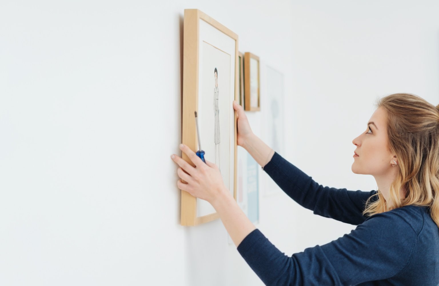 woman hanging a picture on the wall