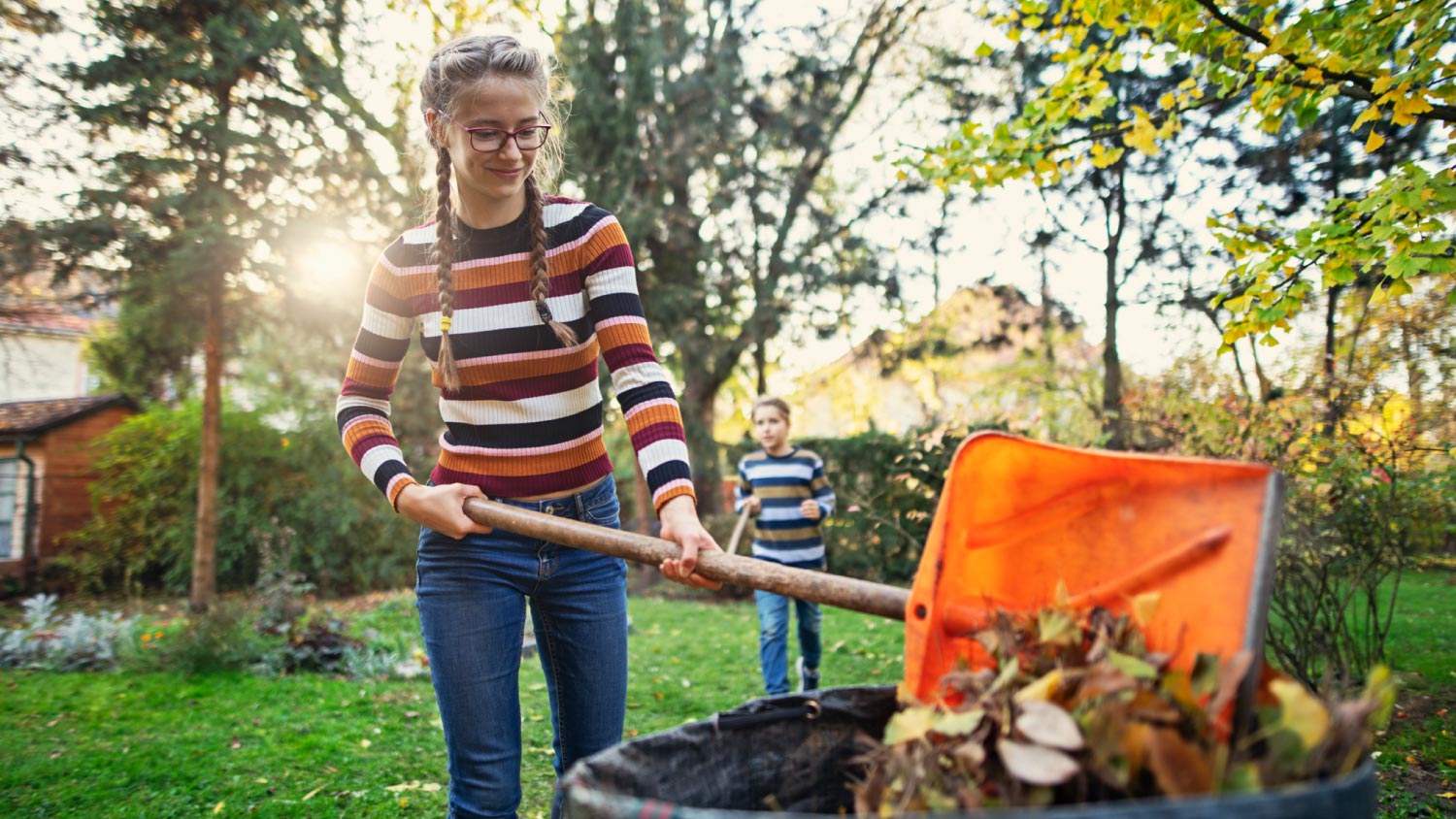 A teenage girl composting autumn leaves