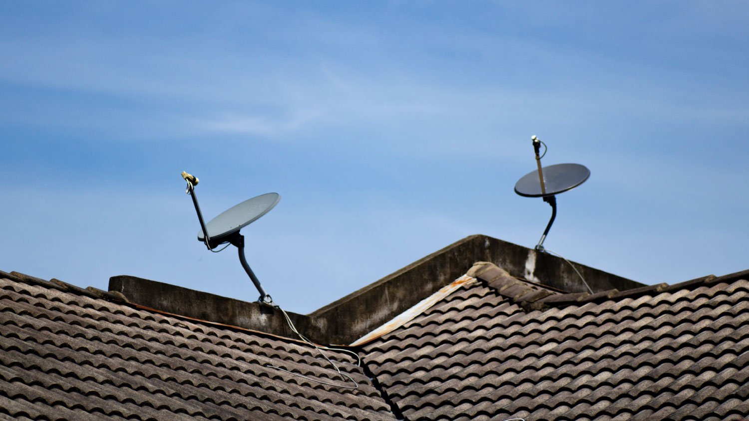 Two satellite dishes on a house roof