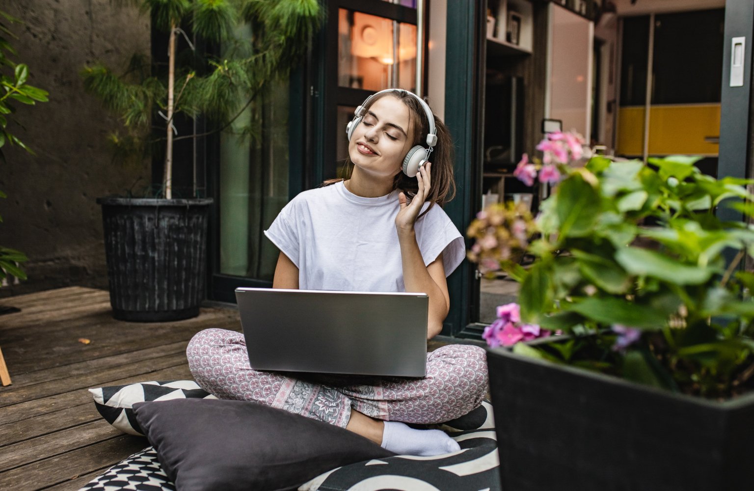 woman with headphones working on computer in backyard patio