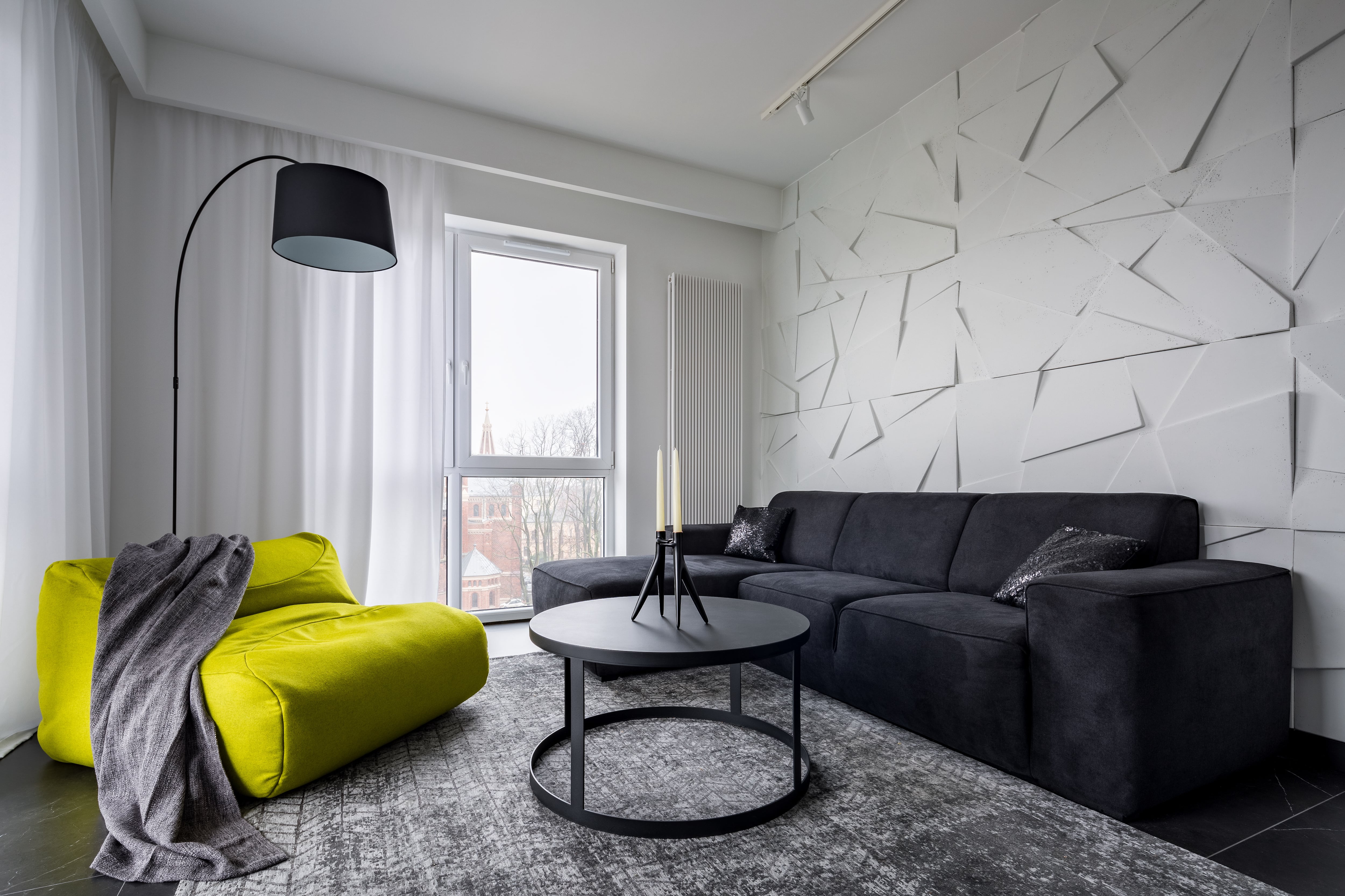 Living room with white geometric 3D wall panel, gray couch, green sack couch, and round coffee table 