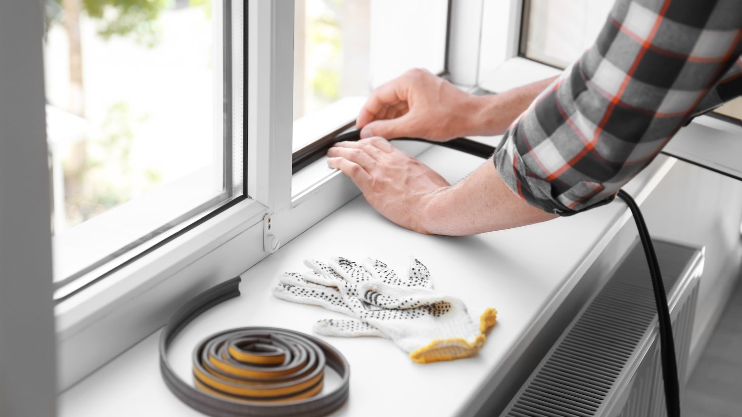 Hands applying window strips to a window frame