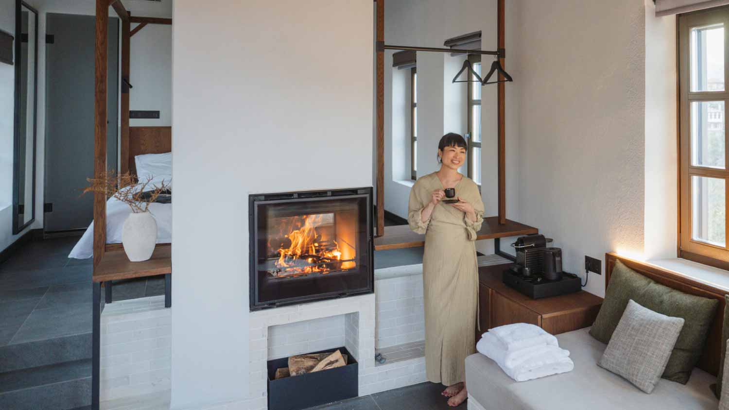 Woman drinking coffee next to the fireplace