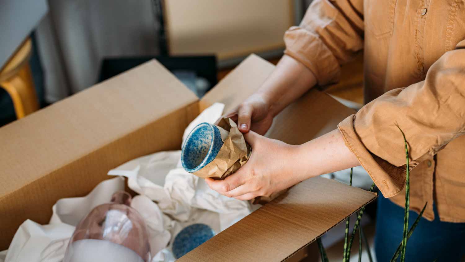 Woman packing up ceramics in paper