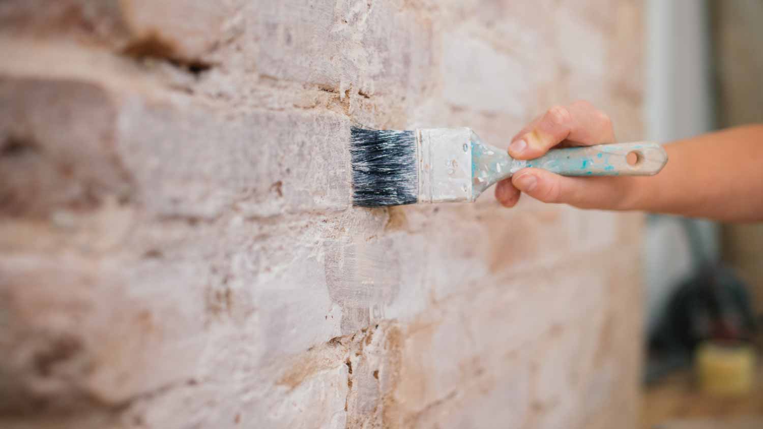 Woman painting a brick wall