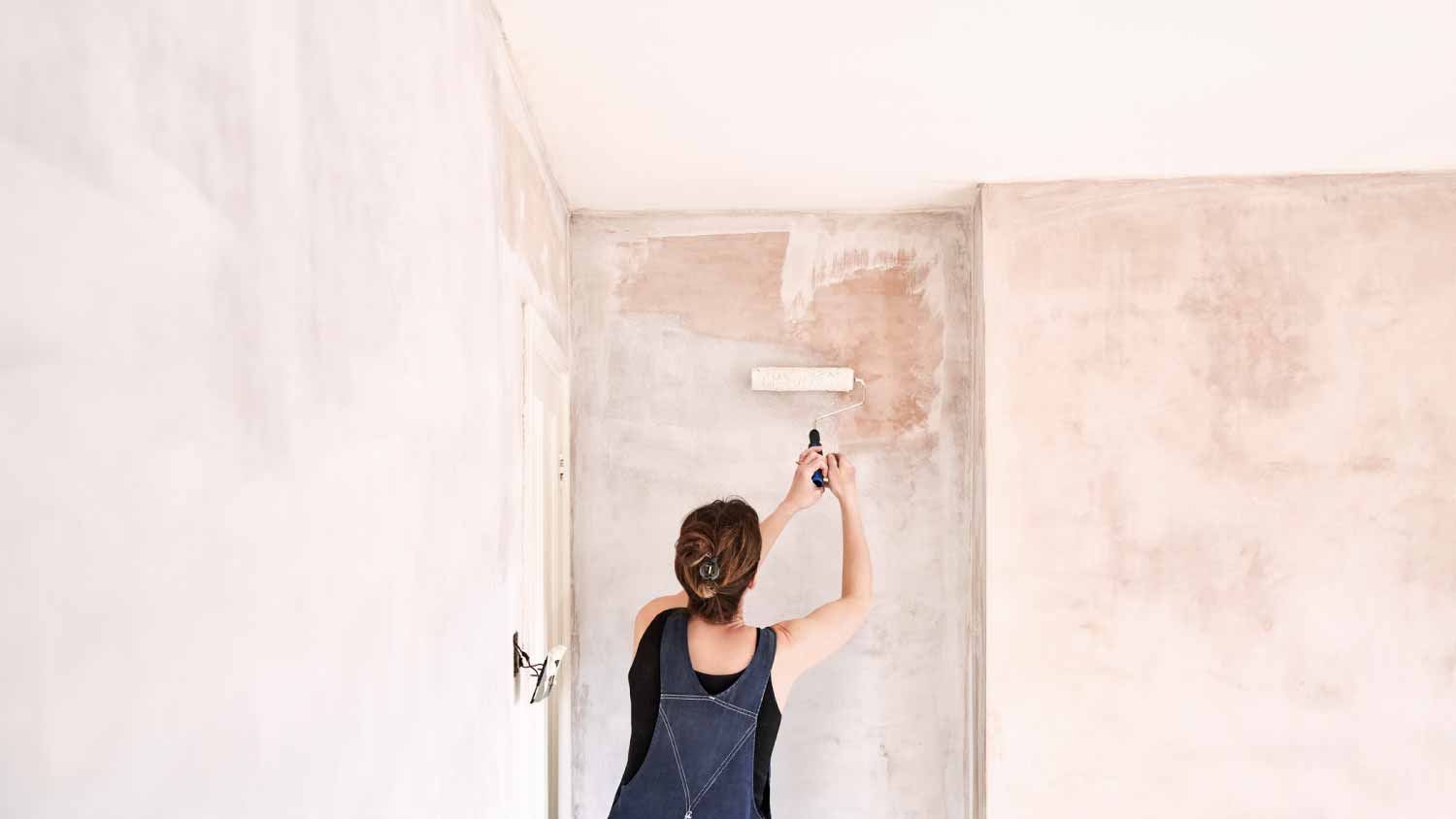 Woman painting newly plastered wall