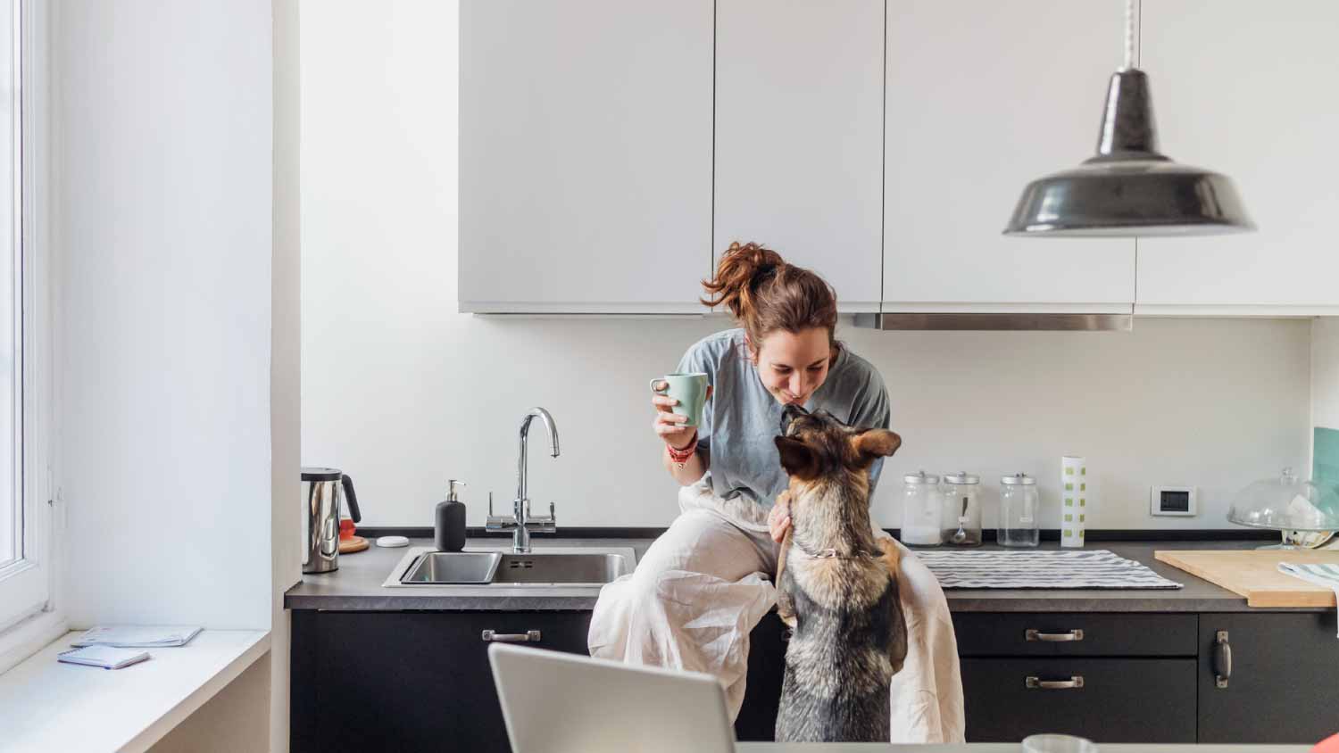 Woman playing with her dog while sitting on kitchen