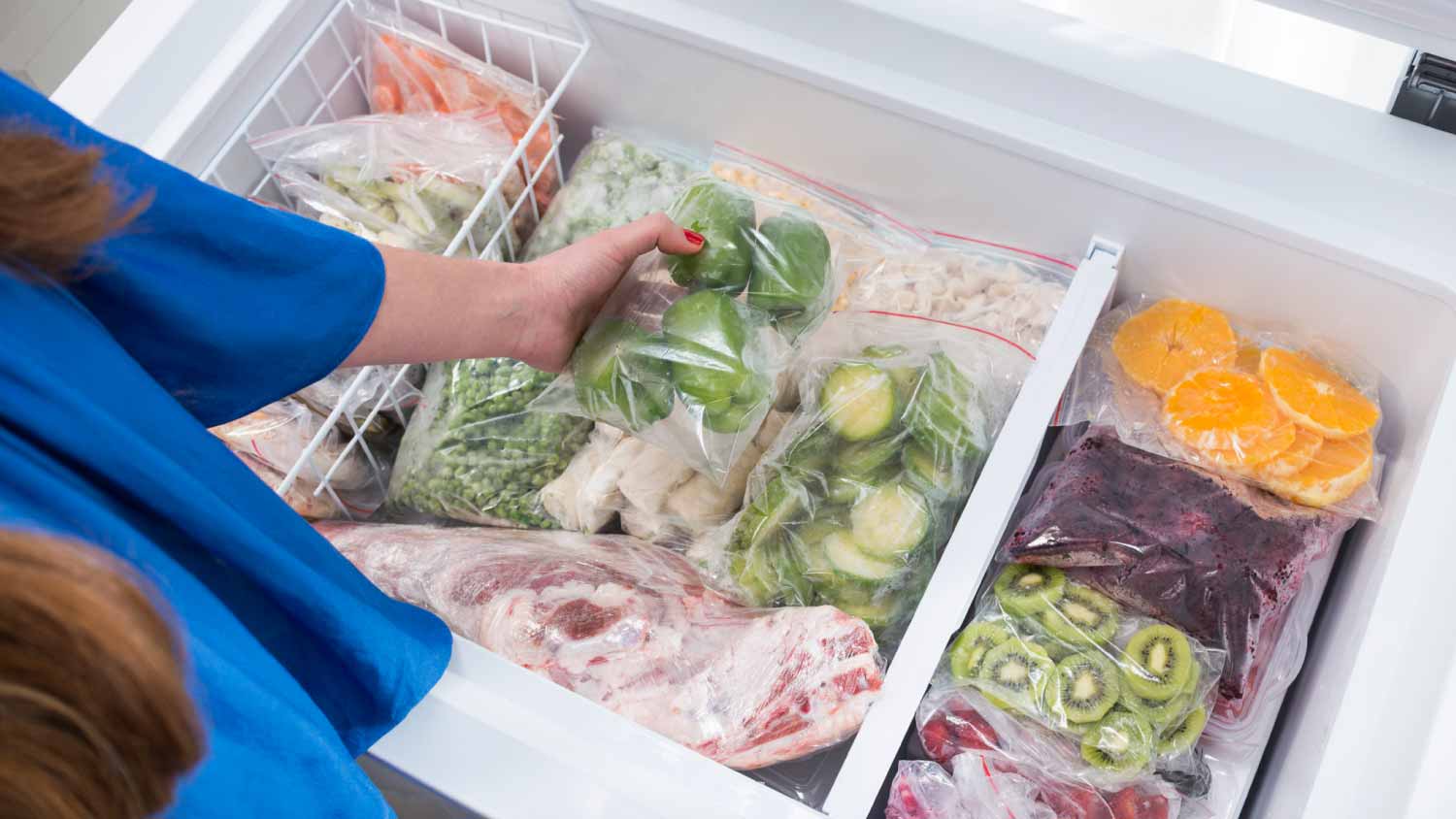 Woman putting green bell peppers in the freezer