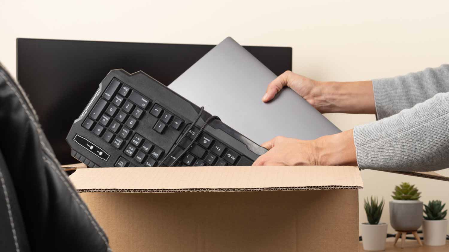 Woman putting old laptop and keyboard in box 