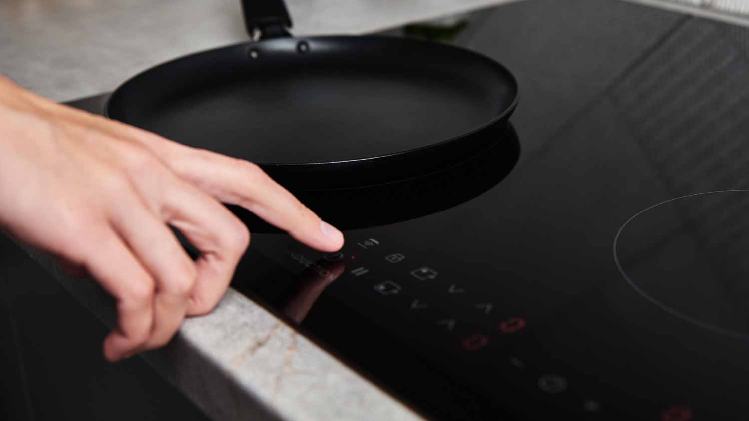 Woman turning on modern induction stove