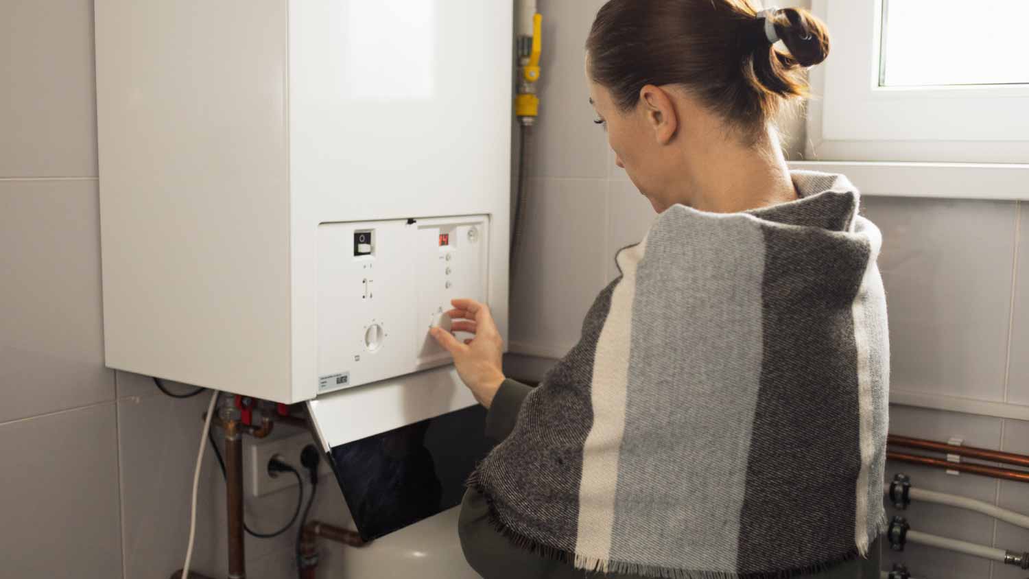 Woman turning on the power of the gas boiler