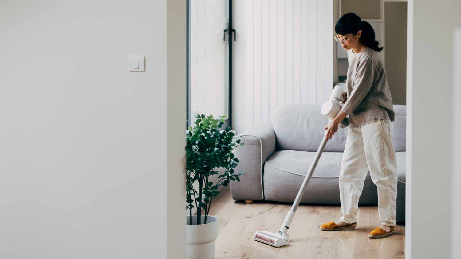 Woman vacuuming wooden floor