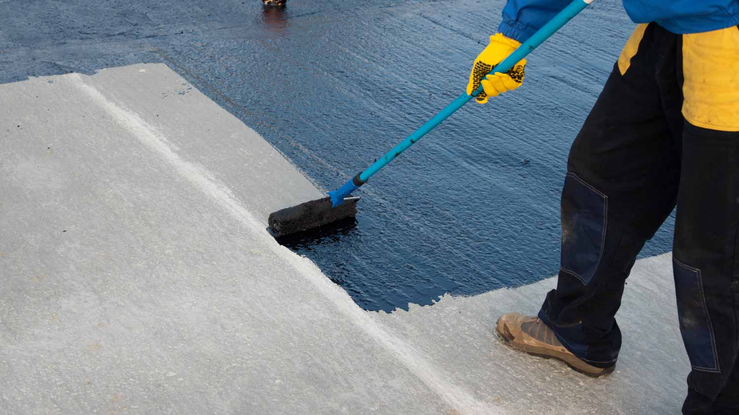 Worker applying bitumen mastic