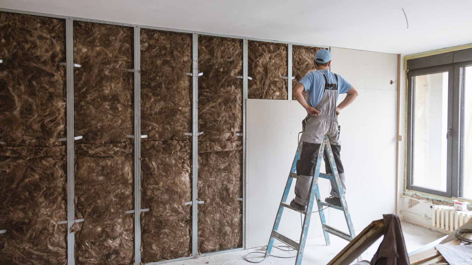 Worker checking drywall installation