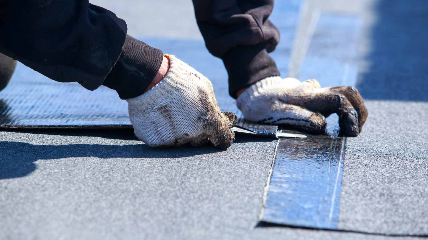 Worker cutting roofing material