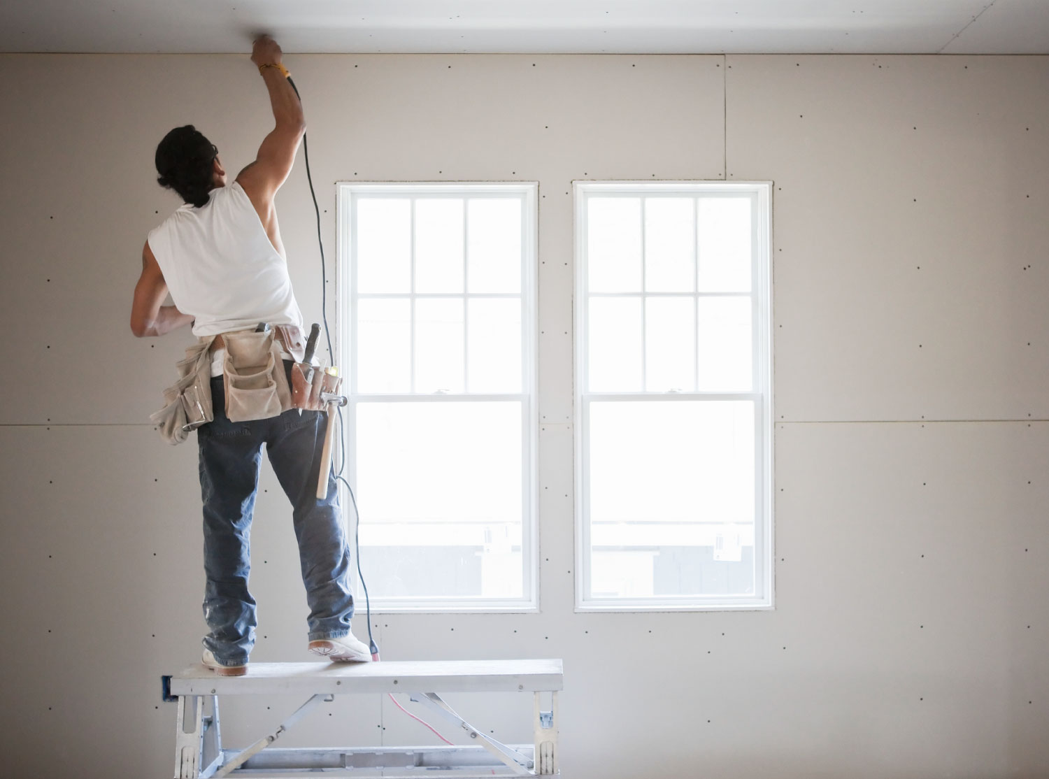 A worker drilling a wall