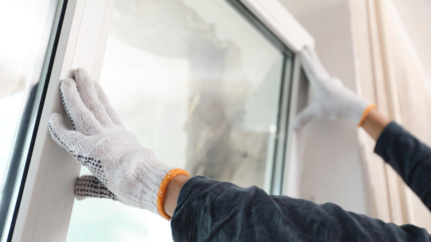 Worker installing plastic window indoors