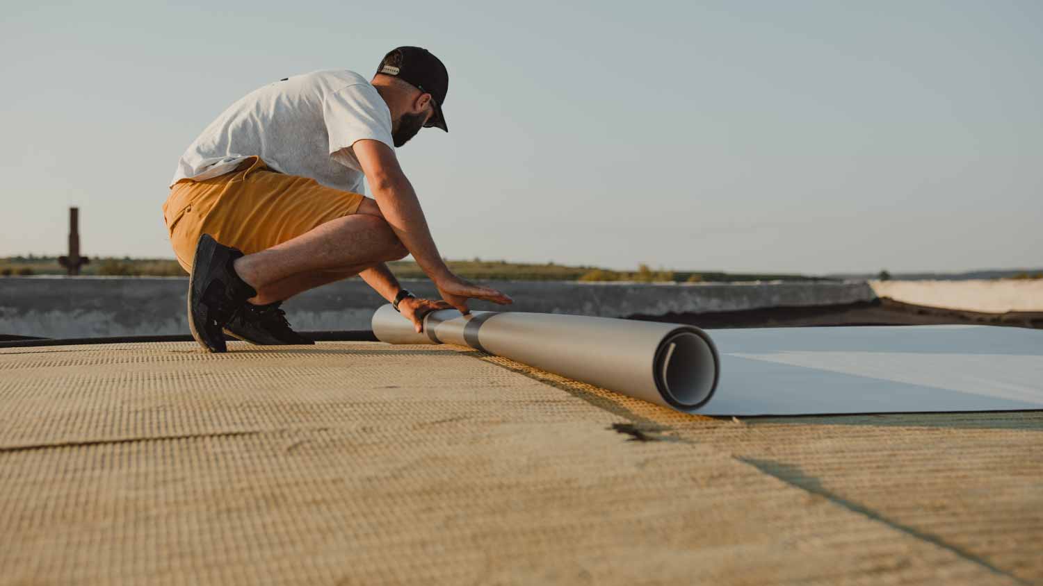 Worker installing pvc membrane roller on roof
