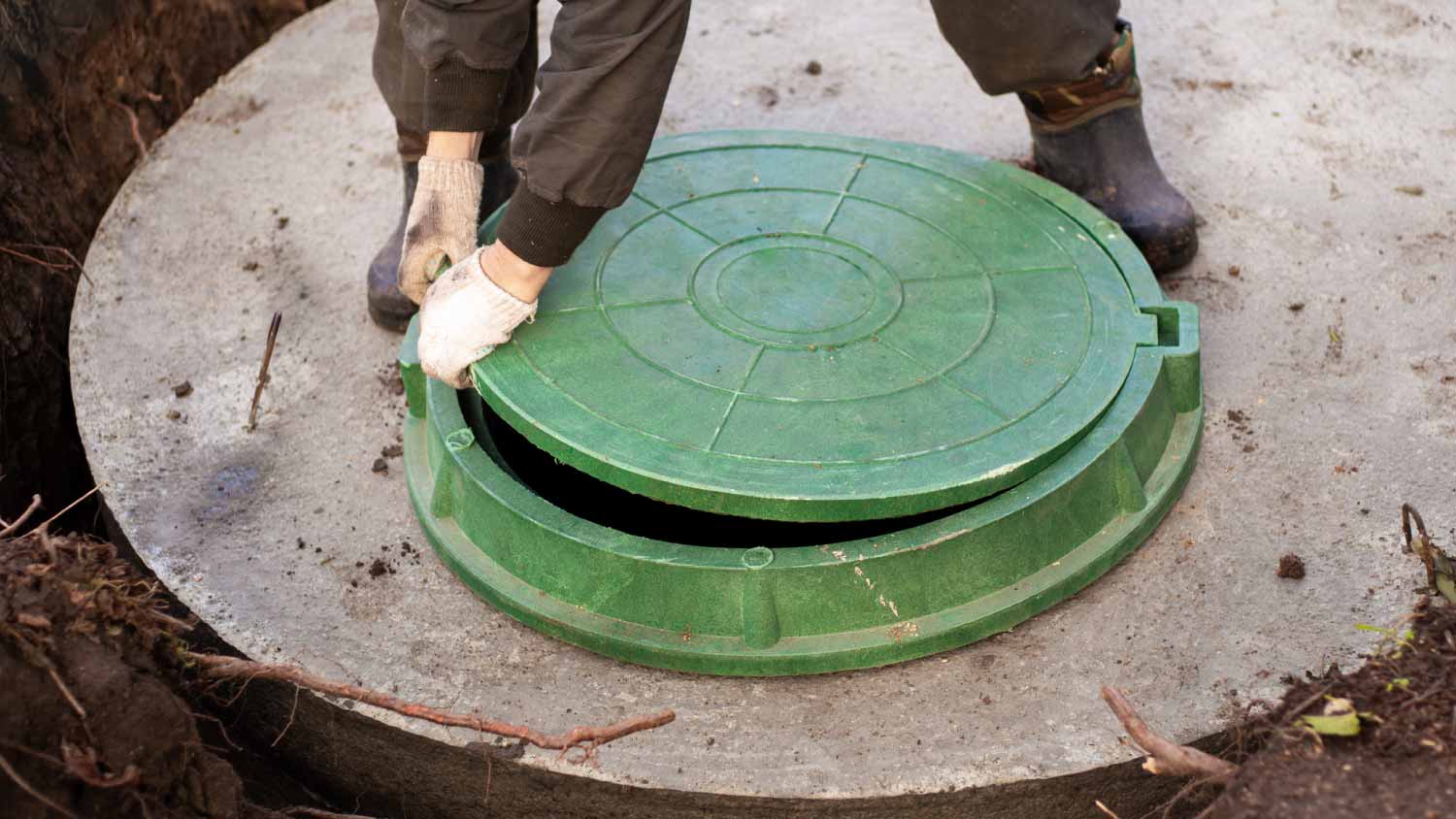 Worker installing a sewer manhole on a septic tank