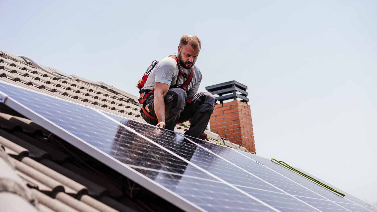 Worker installing solar panels on roof