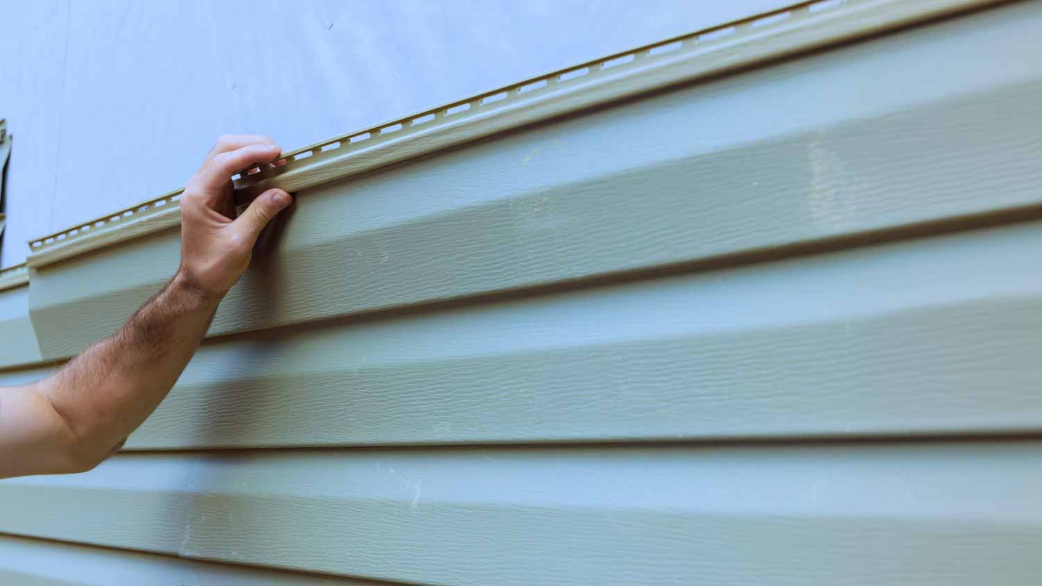 Worker installing vinyl siding plastic panels